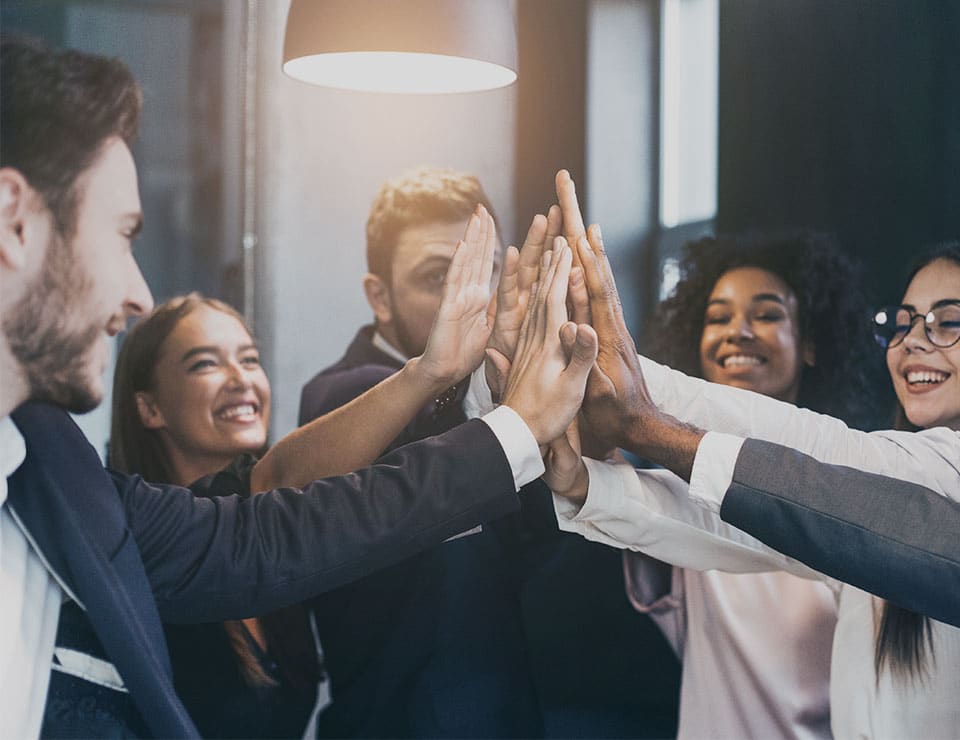 An image of a group of people in a business environment high-fiving that is used for the MetaPerformance Organisational Design Consulting service.